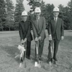 Fr. Monan & 2 other men pose with feet poised on shovels.